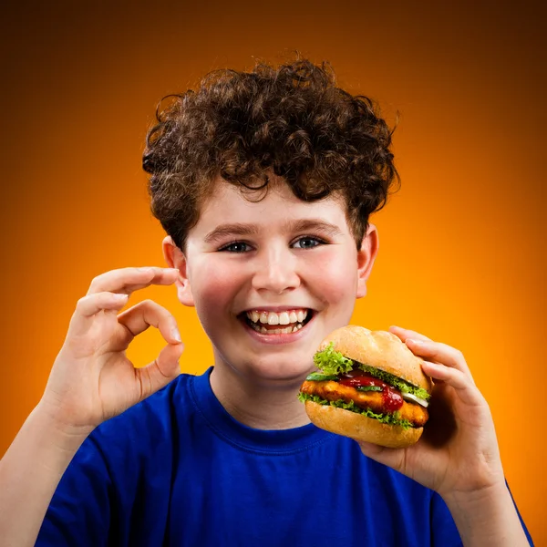 Chico comiendo sándwich grande mostrando señal OK —  Fotos de Stock
