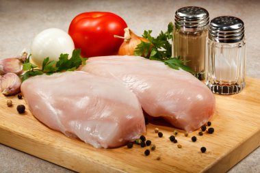 Raw chicken breasts on cutting board clipart