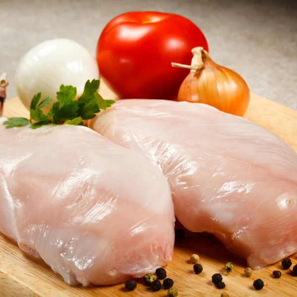 Pechugas de pollo crudas en tabla de cortar —  Fotos de Stock