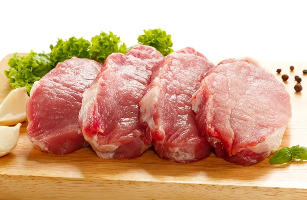 Syrové vepřové maso na řezací desce a zelenině — Stock fotografie