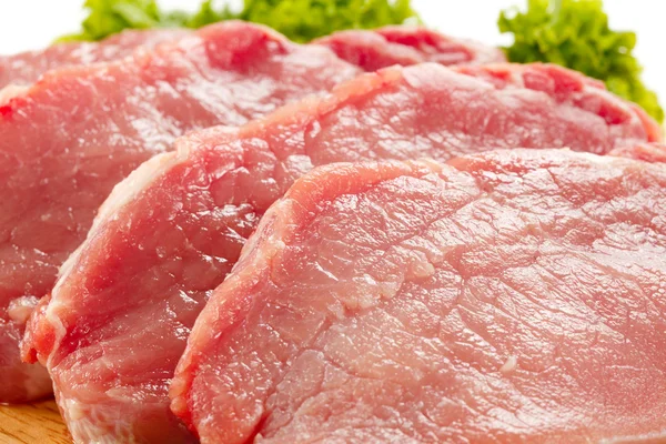 Carne de porco crua sobre tábua de corte e legumes — Fotografia de Stock