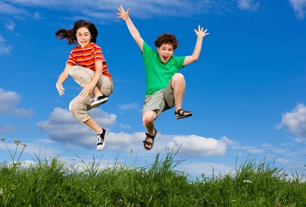 Fille et garçon courir, sauter en plein air — Photo