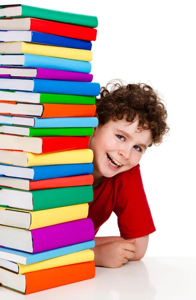 Мальчик за кучей книг, изолированных на белом фоне — стоковое фото