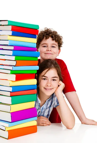 Eleverna sitter bakom högen av böcker på vit — Stockfoto