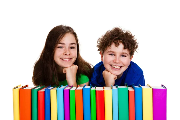 Students sitting behind pile of books on white — Stock Photo, Image