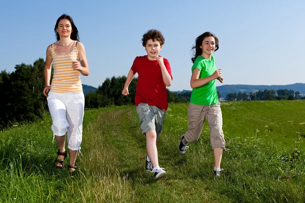 Aktivní rodina - matka a děti, běh, skákání venkovní — Stock fotografie