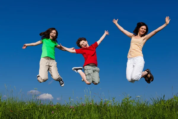 Familia activa - madre e hijos saltando al aire libre — Foto de Stock