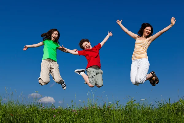 stock image Active family - mother and kids jumping outdoor