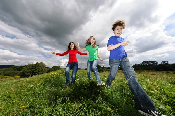 Famille active - mère et enfants courant, sautant en plein air — Photo