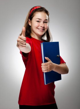 Girl holding book showing OK sign on gray background clipart