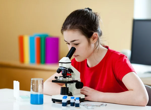 Девушка осматривает препарат под микроскопом — стоковое фото