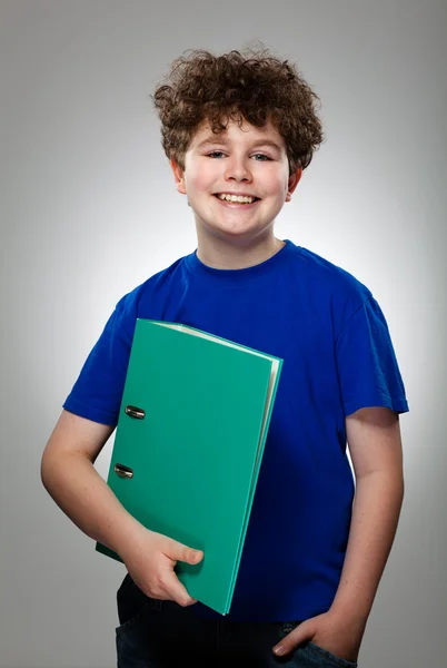 年轻的男孩抱着书上的灰色背景 — 图库照片