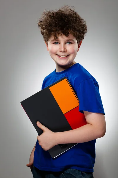 Мальчик держит книги на сером фоне — стоковое фото