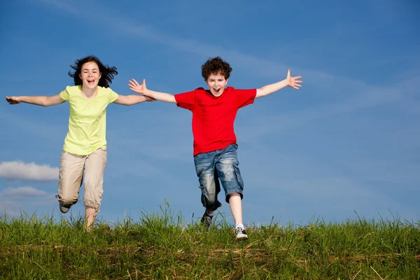 Chica y niño corriendo, saltando al aire libre — Foto de Stock