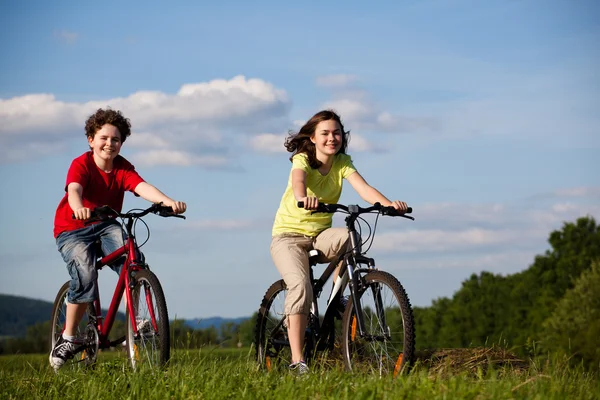 Meisje en jongen paardrijden fietsen — Stockfoto