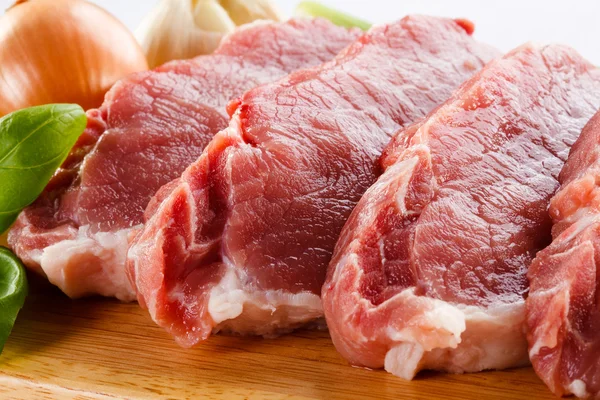 Raw pork on cutting board and vegetables — Stock Photo, Image
