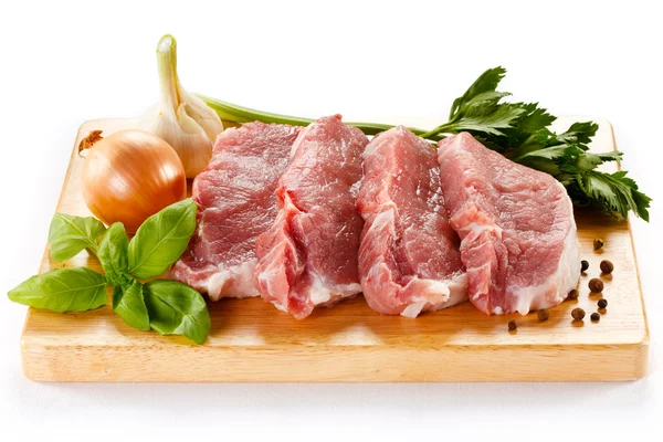 Ωμό χοιρινό κρέας σε ξύλο κοπής και λαχανικά — Φωτογραφία Αρχείου