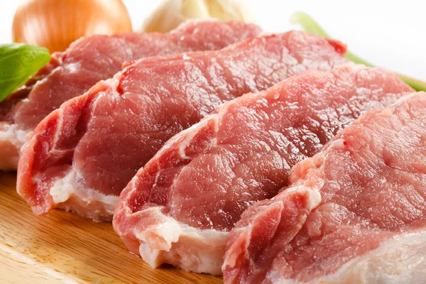 Cerdo crudo en tabla de cortar y verduras —  Fotos de Stock