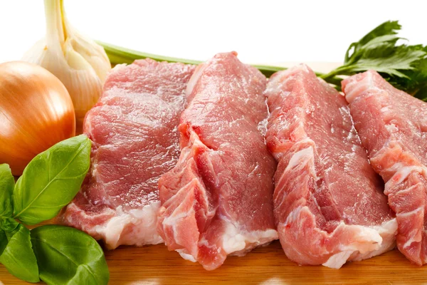 Carne de porco crua sobre tábua de corte e legumes — Fotografia de Stock