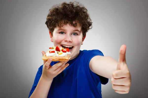Fiú enni tortát tejszínnel és gyümölcsök — Stock Fotó