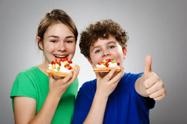 Kinder essen Kuchen mit Sahne und Früchten — Stockfoto