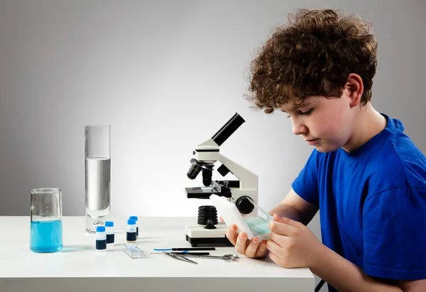 Menino examinando preparação ao microscópio — Fotografia de Stock