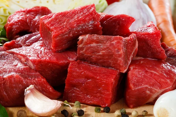 Rohes Rindfleisch auf Schneidebrett und Gemüse — Stockfoto