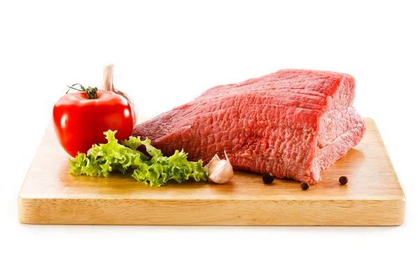 Ruwe rundvlees op snijplank en groenten — Stockfoto
