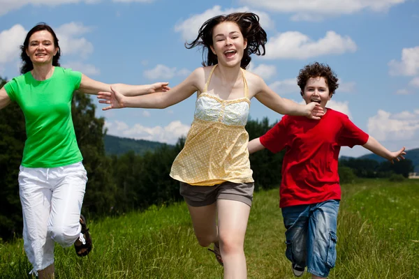 Família ativa - mãe e crianças correndo, pulando ao ar livre — Fotografia de Stock