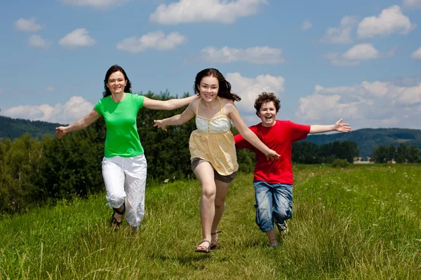 Активна сім'я - мати і діти бігають, стрибають на відкритому повітрі — стокове фото