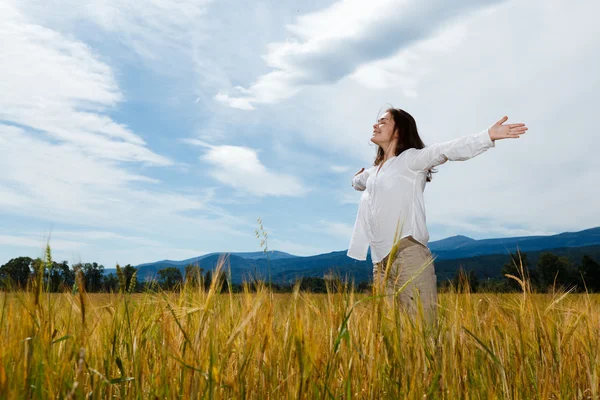 Girl holding arms up against blue sky — Stock Photo, Image