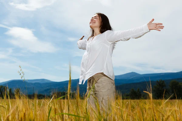 Girl holding arms up against blue sky Stock Picture