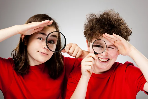 Девочка и мальчик держат увеличительное стекло — стоковое фото