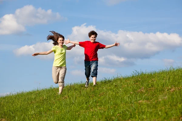 Девочка и мальчик бегут, прыгают на открытом воздухе — стоковое фото