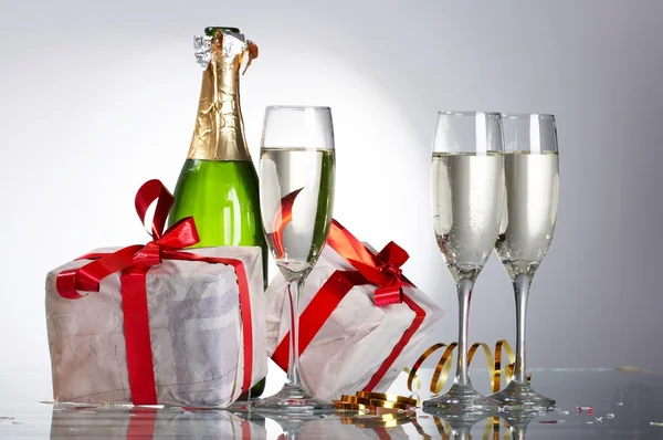 Glas champagne, gåvor med röda band och rosetter — Stockfoto