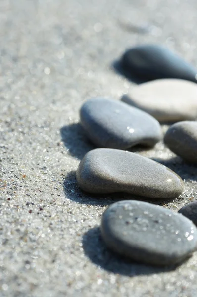 Stenen op zand op de zee, een kiezelsteen — Stockfoto