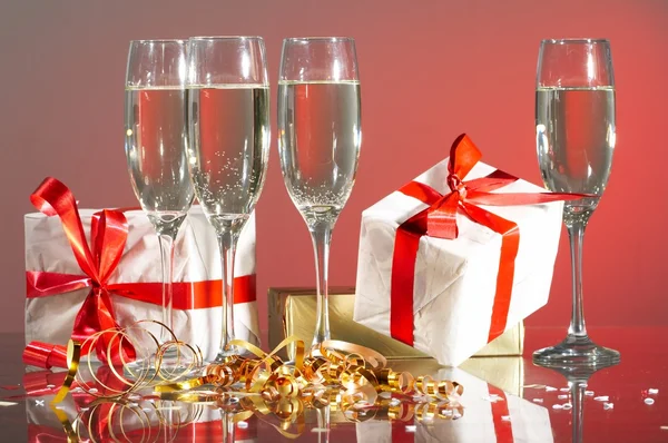 Glasses of champagne, gifts with red tapes and bows — Stock Photo, Image