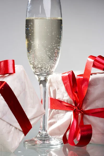 Copos de champanhe, presentes com fitas vermelhas e arcos — Fotografia de Stock