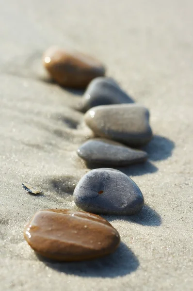 Камни на песке у моря, галька — стоковое фото