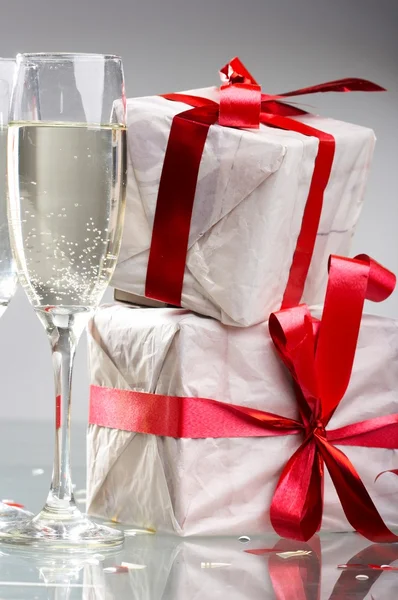 Lunettes de champagne, cadeaux avec rubans rouges et noeuds — Photo
