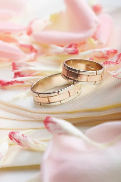 Złote pierścienie i płatki róży — Zdjęcie stockowe
