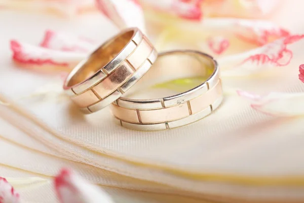 Золотые кольца и лепестки роз — стоковое фото