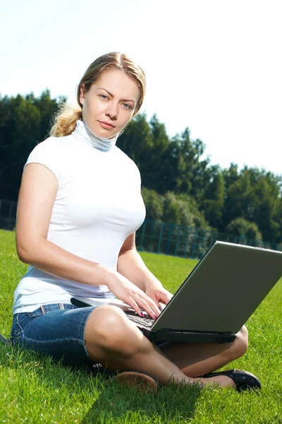 Flickan med laptop på en grön gräsmatta — Stockfoto