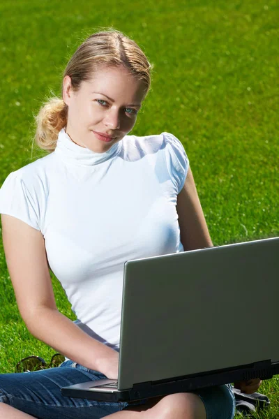 La muchacha con el portátil sobre el césped verde —  Fotos de Stock