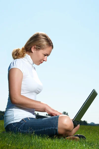 La muchacha con el portátil sobre el césped verde — Foto de Stock