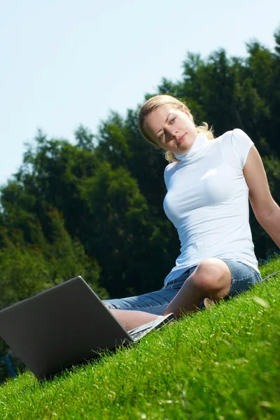 Девушка с ноутбуком на зеленой лужайке — стоковое фото