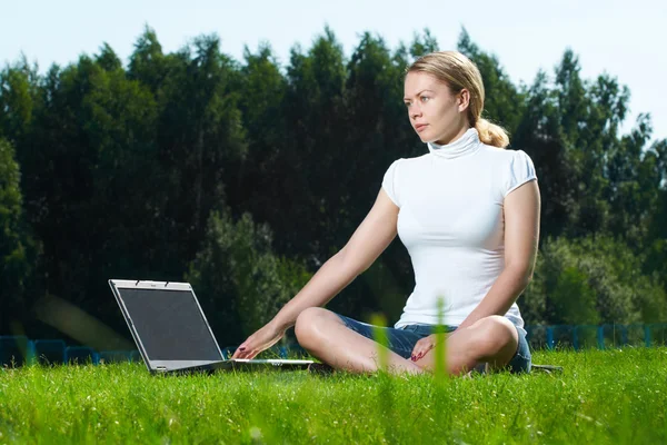 Девушка с ноутбуком на зеленой лужайке — стоковое фото