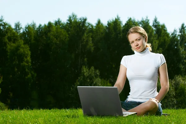 与绿色的草坪上的笔记本电脑女孩 — 图库照片