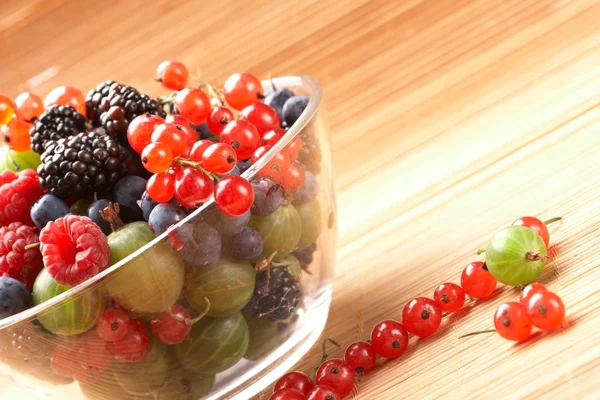 Mélange de fruits dans le récipient en verre, sur une table de paille — Photo