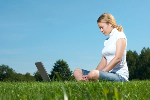 Het meisje met laptop op een groene gazon — Stockfoto